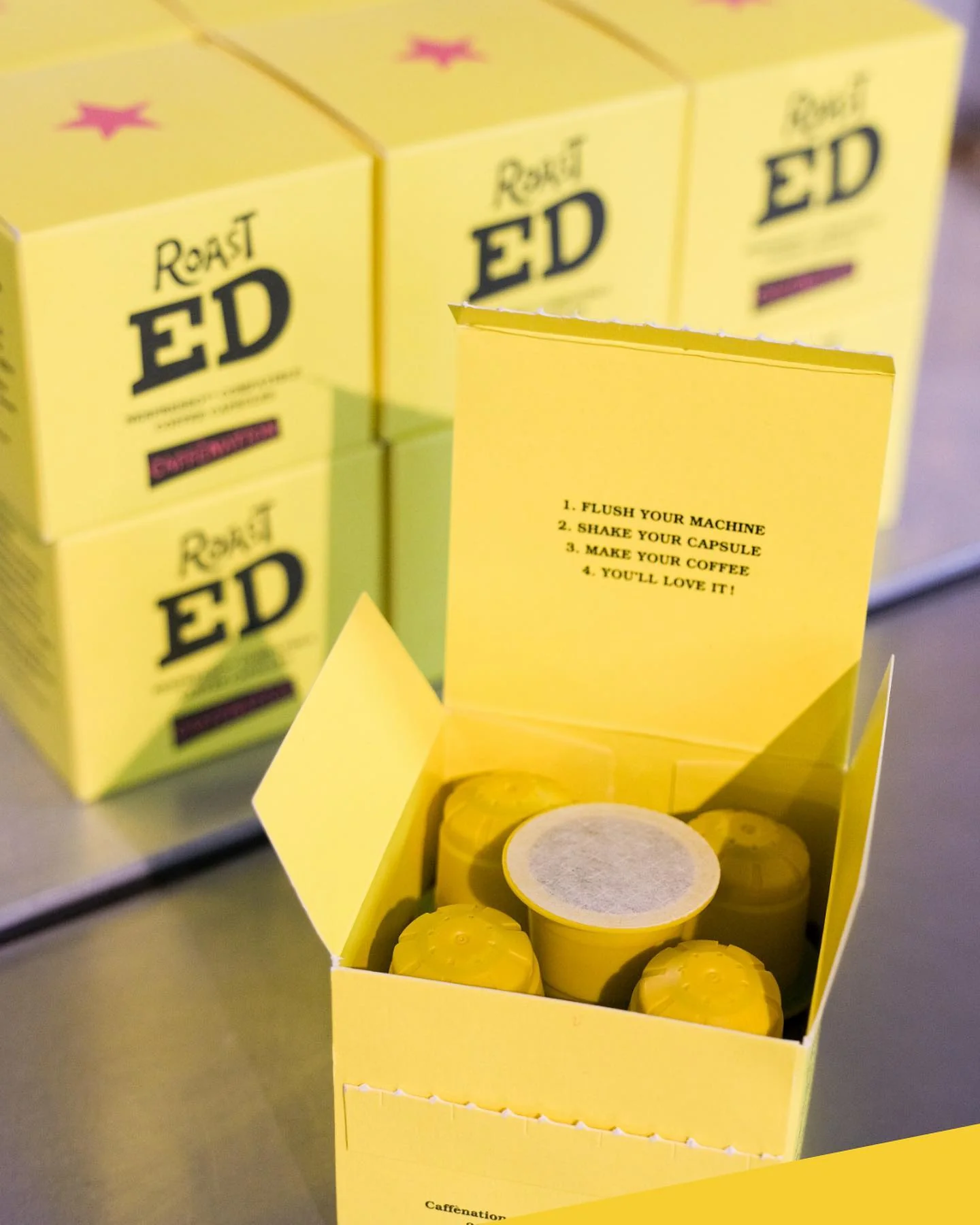 An open yellow Roast ED capsule box with compostable coffee capsules inside